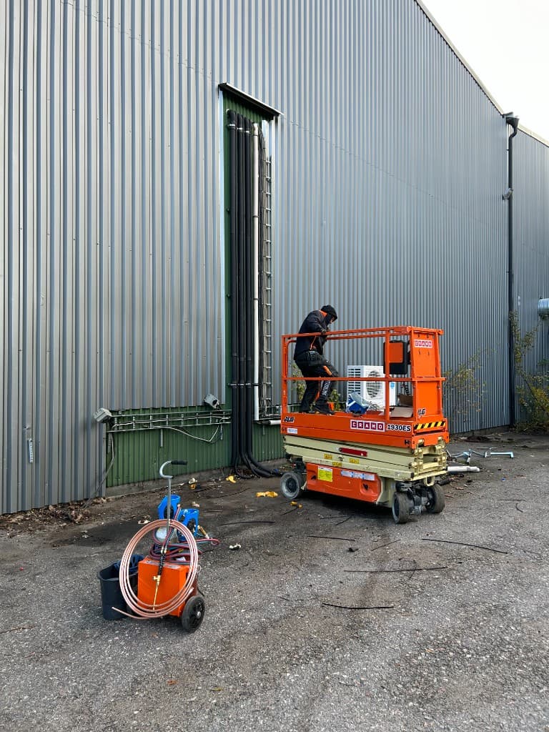 Tekniker monterar rördragning och kylinstallation från saxlift